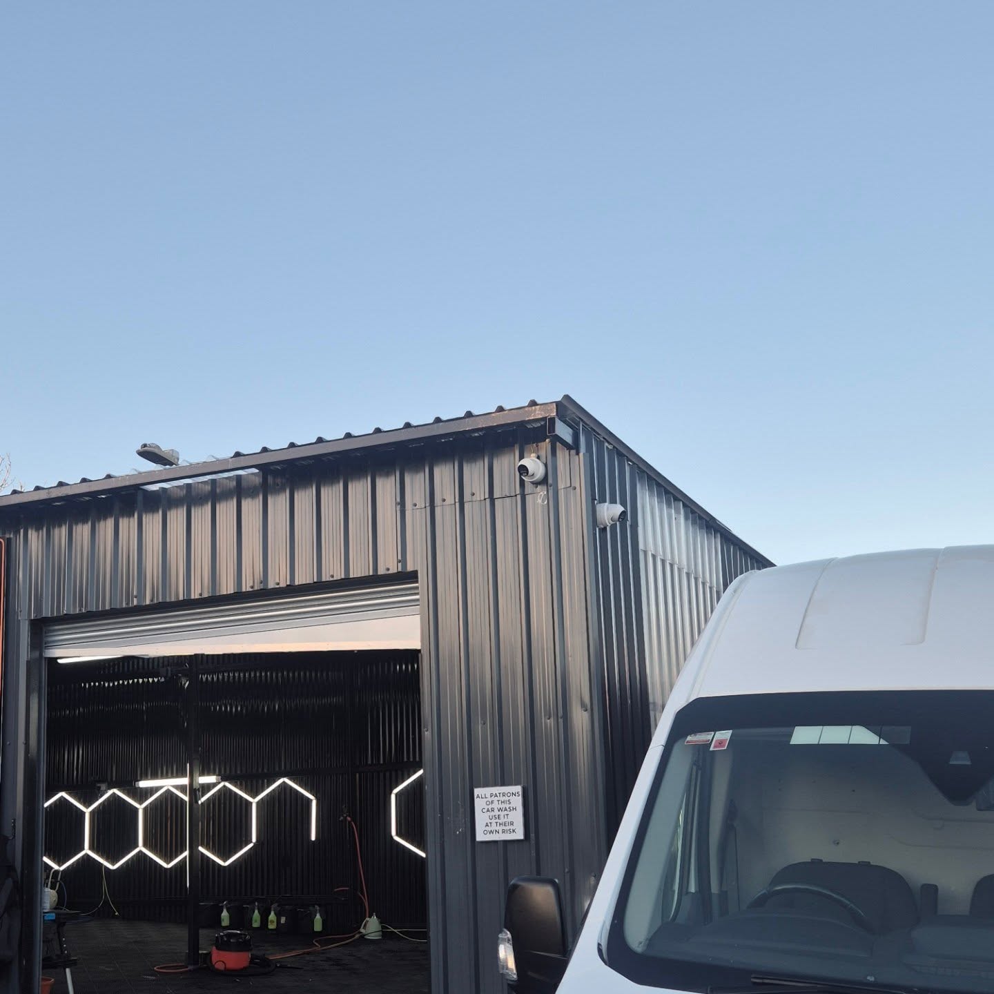 Two wired IP cameras mounted high on the corner of a commercial car wash unit, with the Stainthorpe van parked alongside